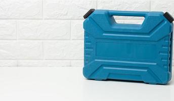 geschlossen Blau Plastik Werkzeug Fall steht auf ein Weiß Tabelle foto