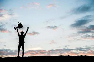 Silhouette Mann hält eine Trophäenschale hoch foto