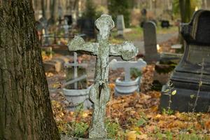 geknackt Stein Christian Kreuz im ein orthodox Friedhof im Herbst foto