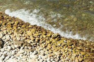 Kieselsteine und Stein auf das Meer Küste, Küste mit Ozean Wellen foto
