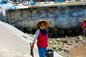 Yogyakarta, Indonesien im November 2022. weiblich Fischer Wer sind ebenfalls Fisch Verkäufer beim Baron Strand sind Waschen ihr Ausrüstung foto