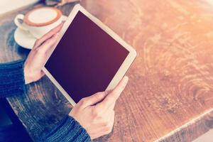 asiatisch Frau Hand halten Tablette und mit Tablette im Kaffee Geschäft mit Jahrgang getönt. foto