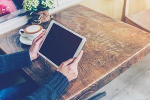 Frau mit Tablette im Kaffee Geschäft mit Jahrgang Ton. foto