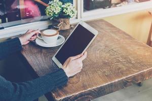 schließen oben Hand Frau mit Tablette im Kaffee Geschäft mit Jahrgang Ton. foto