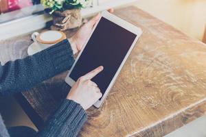 schließen oben Hand Frau mit Tablette im Kaffee Geschäft mit Jahrgang Ton. foto