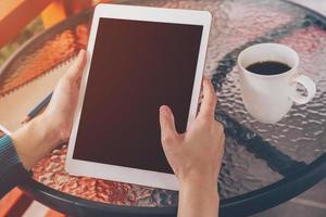 Hand Frau mit Tablette auf Tabelle im Kaffee Geschäft mit Jahrgang getönt. foto