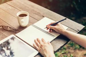 weiblich Hand mit Bleistift Schreiben auf Notizbuch. Frau Hand mit Bleistift Schreiben auf Notizbuch beim Kaffee Geschäft. foto