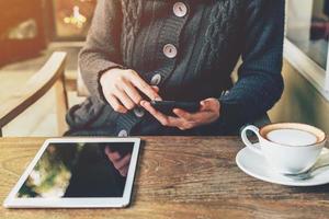 asiatisch Frau mit Telefon im Kaffee Geschäft und Sonnenlicht mit Jahrgang Filter. foto