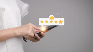 Hand drücken auf Smartphone Bildschirm mit Gold fünf Star Bewertung Feedback Symbol und Drücken Sie Niveau Ausgezeichnet Rang zum geben Beste Ergebnis Punkt zu Rezension das Bedienung , Geschäft Konzept foto