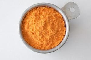 Cheddar Käse Pulver im ein Messung Tasse foto