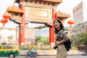 jung asiatisch Frau Rucksack Reisender genießen China Stadt, Dorf Straße Essen Markt im Bangkok, Thailand. Reisender Überprüfung aus Seite Straßen. foto