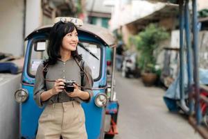 jung asiatisch Frau Rucksack Reisender Stehen ein Seite von Tuk Tuk Taxi auf Sommer- Urlaube beim Bangkok, Thailand. foto