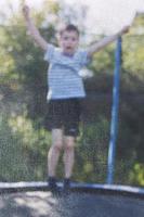 Junge Springen auf Trampolin. das Kind Theaterstücke auf ein Trampolin draussen foto