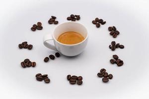 Kaffee Bohnen bilden ein Uhr mit ein dämpfen Tasse von Kaffee im das Center, mit ein Weiß Hintergrund foto