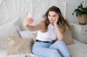 ein glücklich Frau hat ein Selfie. das Mädchen sieht aus in das Telefon Kamera und lächelt. foto