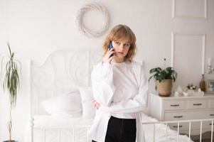 ein Zuhause unterrichtet Student. Stehen mit ein Telefon im ein Weiß Zimmer foto