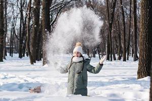 ein Mädchen im Brille und warm Kleider genießt das Schnee im ein Winter Park. Spiele im Natur. foto