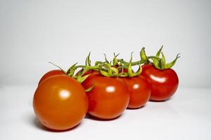 frisch Tomaten Ast isoliert auf Weiß Hintergrund mit lecker und gesund Essen eben legen Seite Aussicht foto