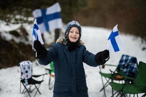 finnisch Junge mit Finnland Flaggen auf ein nett Winter Tag. nordisch skandinavisch Personen. foto