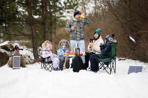 Familie mit drei Kinder im Winter Wald Ausgaben Zeit zusammen auf ein Picknick. foto