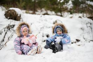 zwei Schwestern im Winter Wald mit ausgestopft Einhorn Spielzeuge. foto