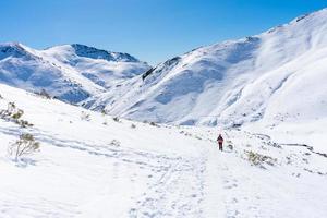 Schneeschuh Bergsteiger sinkt ab Pfad in schneebedeckt Berge foto