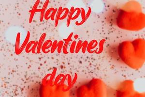 glücklich Valentinstag Tag Text auf verschwommen Rosa Hintergrund mit Herzen. foto