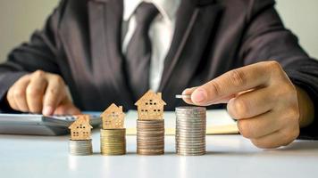 Holzhausmodell auf Münzen und Menschenhänden, Immobilieninvestitionsideen und Finanztransaktionen