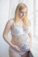 glücklich schwanger Frau mit ein nett Zeichnung auf ihr Bauch foto