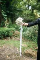Nahaufnahme des Bräutigams mit schönem Blumenstrauß in den Händen für Braut