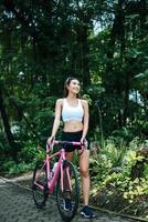 Porträt einer Frau mit einem rosa Fahrrad im Park foto