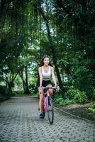 Porträt einer Frau mit einem rosa Fahrrad im Park foto