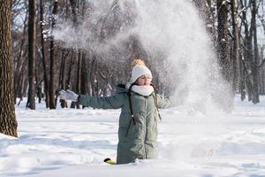 ein Mädchen im Brille und im warm Kleider Theaterstücke mit Schnee im ein Winter Park. Spaziergänge im das Luft. foto