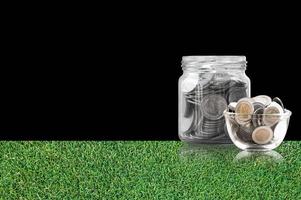 Münzen im ein Glas Krug auf Gras Fußboden ,Ersparnisse Münzen - - Investition und Interesse Konzept Speichern Geld Konzept, wachsend Geld auf Schweinchen Bank. isoliert auf schwarz Hintergrund foto