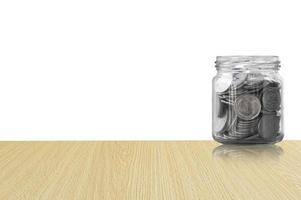 Münzen im ein Glas Krug auf Holz Fußboden ,Ersparnisse Münzen - - Investition und Interesse Konzept Speichern Geld Konzept, wachsend Geld auf Schweinchen Bank. isoliert auf Weiß Hintergrund foto