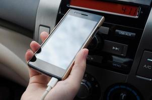 Hand halt Smartphone im Auto-Ladegerät Stecker Telefon auf Auto, Leute Drücken Sie das Telefon während Fahren foto