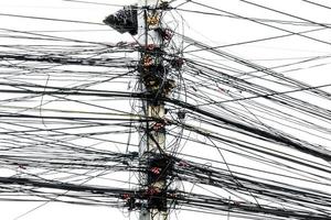 Unordentliches Chaos von Kabeln mit Drähten auf Strommasten auf weißem Hintergrund, die vielen elektrischen Drähte an den Strommasten foto