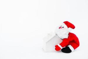 Santa claus Puppe halten ein klein hölzern Haus auf isoliert auf Weiß Hintergrund, Weihnachten Dekoration foto