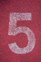 Nummer fünf auf Laufen Schiene. Weiß Spur Nummer auf rot Gummi Rennstrecke, Textur von Laufen Rennstrecken im Stadion foto