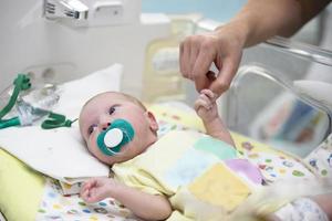 das Arzt Hand hält das Hand von ein Neugeborene Baby im ein medizinisch Kasten. foto