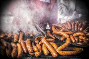 ein Nahansicht Aussicht von Hände von ein Mann Grillen hausgemacht Würste foto