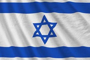 israel-flagge mit großen falten, die unter dem studiolicht im innenbereich wehen. die offiziellen symbole und farben im banner foto