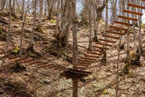 Seilpark mitten im Wald. Sporthindernisse über dem Boden passieren. Outdoor-Aktivitäten. Sportpark für die ganze Familie. Hängetreppen und Seile zwischen Bäumen gespannt. Holzstadt foto