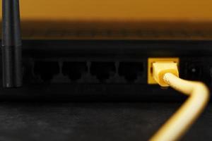 ein Gelb Patch Kabel ist eingefügt in das W-lan Hafen von das Router zu Zugriff das Internet. foto