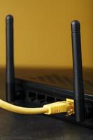 ein Gelb Patch Kabel ist eingefügt in das W-lan Hafen von das Router zu Zugriff das Internet. foto