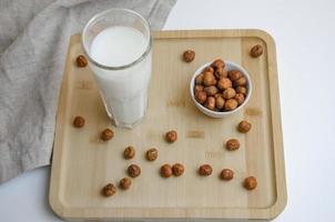 auf ein hölzern Tafel Haselnuss Nüsse und ein Glas von Milch, das Konzept von Milch von Nüsse foto