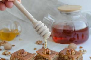 Baklava auf ein Tafel auf ein Licht Hintergrund Nächster zu Nüsse, Honig und Rosinen foto