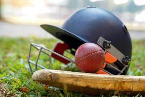 Cricket-Ausrüstung ist ein Cricket-Ball, ein Cricket-Schläger, ein Cricket-Helm auf einem Grashintergrund. weicher und selektiver Fokus. foto