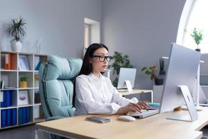 asiatisch Geschäftsfrau Arbeiten im modern Büro beim Computer, Tippen online Bericht foto