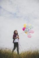 schöne junge Hipsterfrau, die bunte Luftballons draußen hält foto